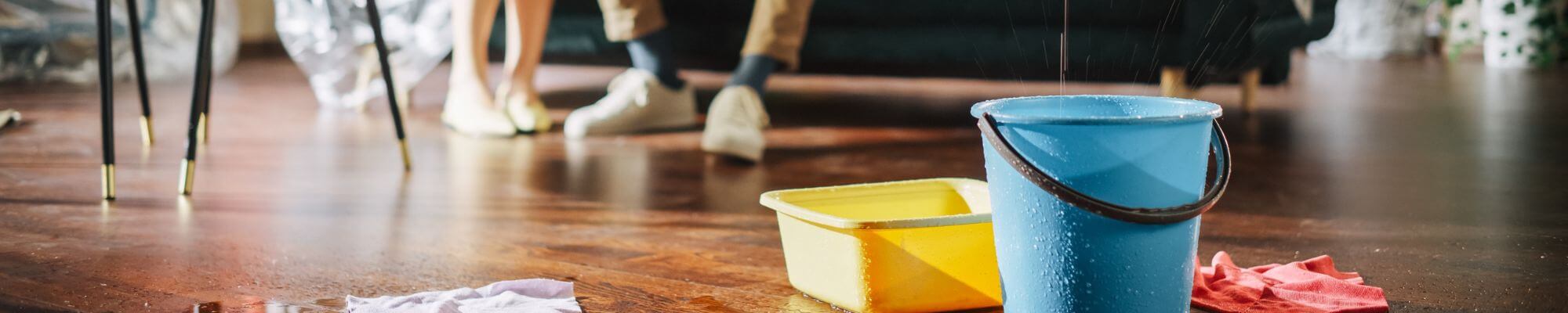 Le toit fuit un couple de paniers En désespoir de cause assis sur un canapé regardant comment l'eau se déverse dans des seaux dans leur salon.